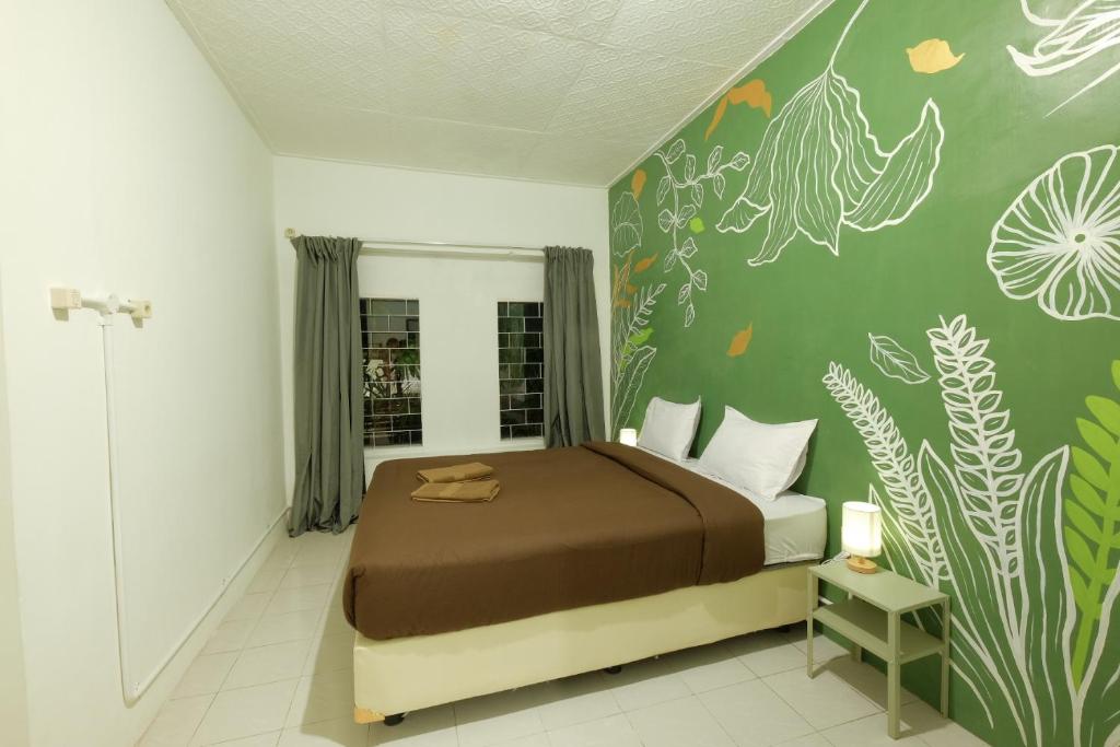 a bedroom with a bed and a wall with plants at Snooze Malang in Malang