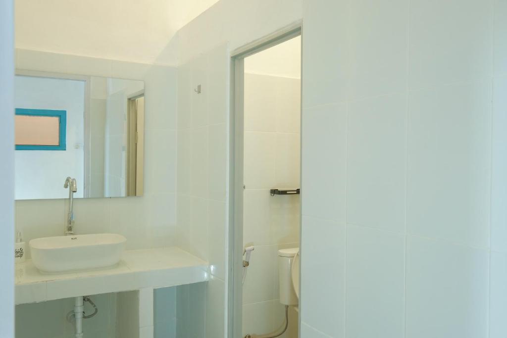a white bathroom with a sink and a mirror at Snooze Malang in Malang