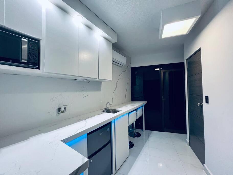 a white kitchen with a sink and a microwave at Departamento ejecutivo nuevo in Ciudad Obregón