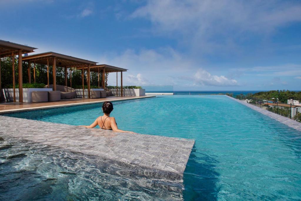 una mujer sentada en una piscina en un resort en Mida Grande Resort Phuket Official Account en Surin Beach