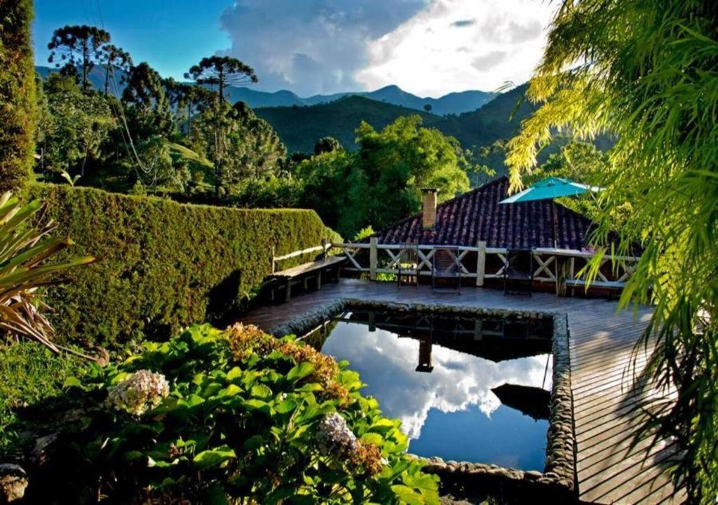 una casa con piscina en un jardín en Pousada Das Araucárias, en Visconde De Maua