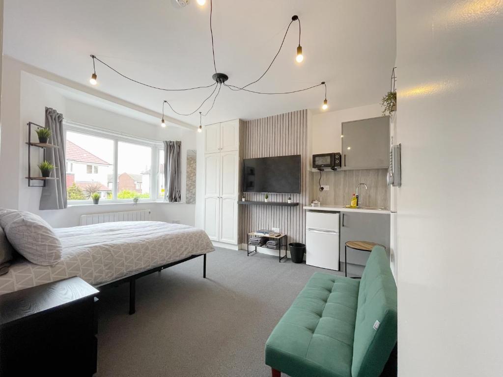 Cosy Bright Studio Apartment Close to Wembley Stadium في لندن: غرفة نوم بسرير واريكة ومطبخ