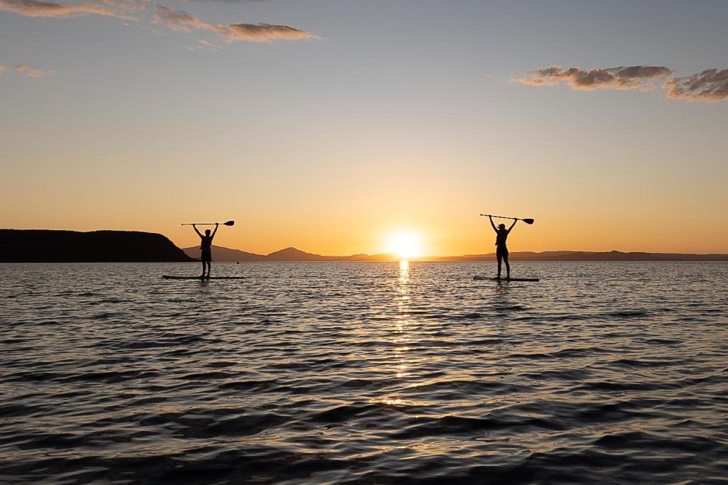 two people on paddle boards in the water at sunset at Waitahanui Lodge in Waitahanui