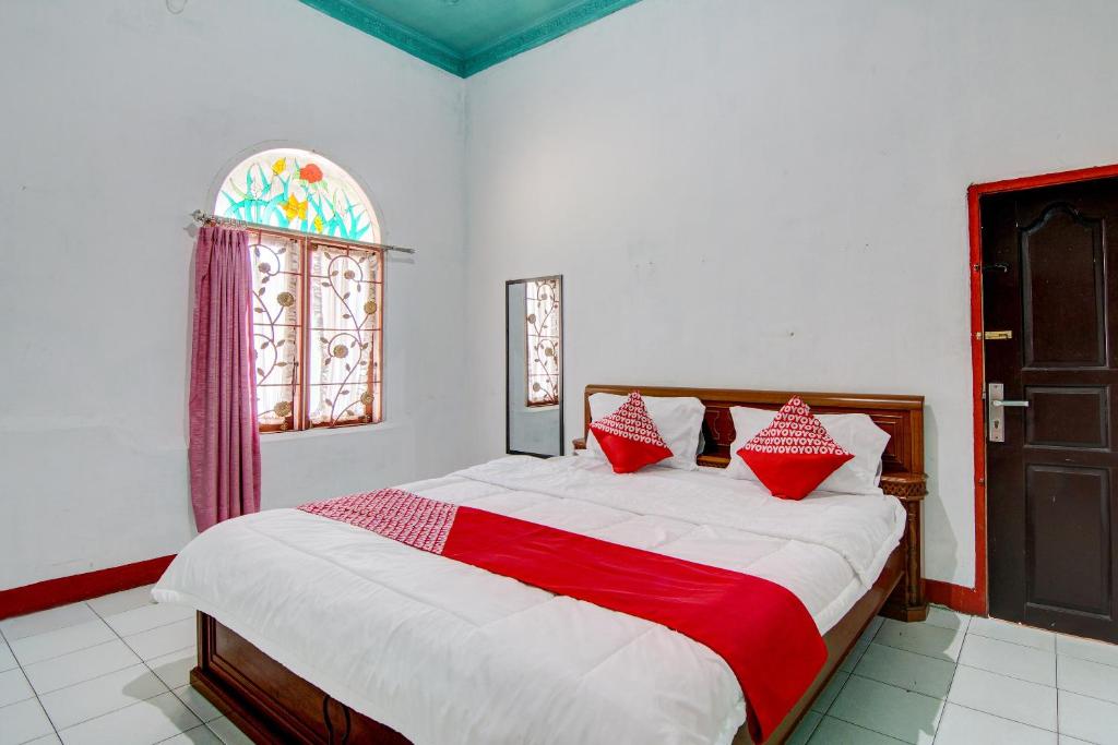 Schlafzimmer mit einem Bett mit roten und weißen Kissen in der Unterkunft OYO 92501 Wisma Sakinah Syariah in Rambah