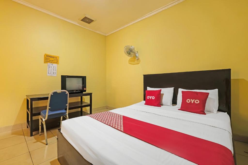 a bedroom with a bed with red pillows and a desk at OYO 92485 Hotel Family in Salatiga