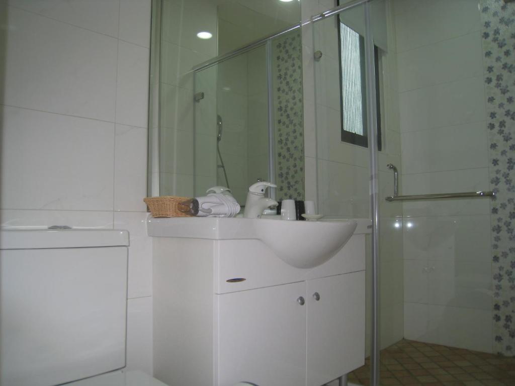 a white bathroom with a sink and a shower at Silia Hostel in Ji&#39;an