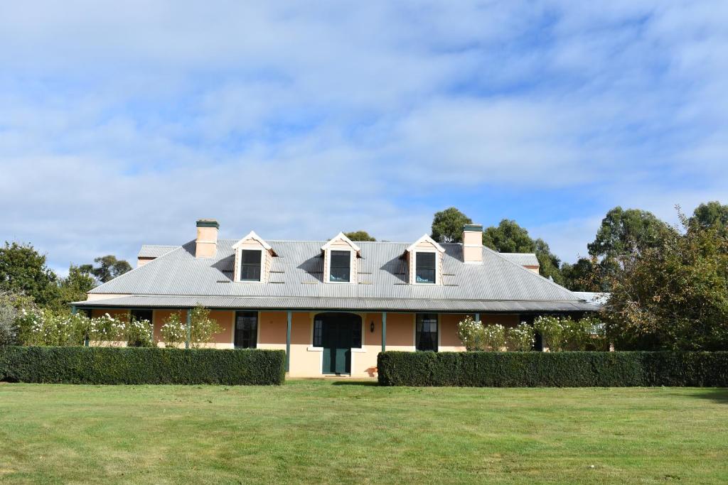 a white house with a gray roof on a field at CLAYFIELD HOMESTEAD - rustic country accommodation in Bishopsbourne