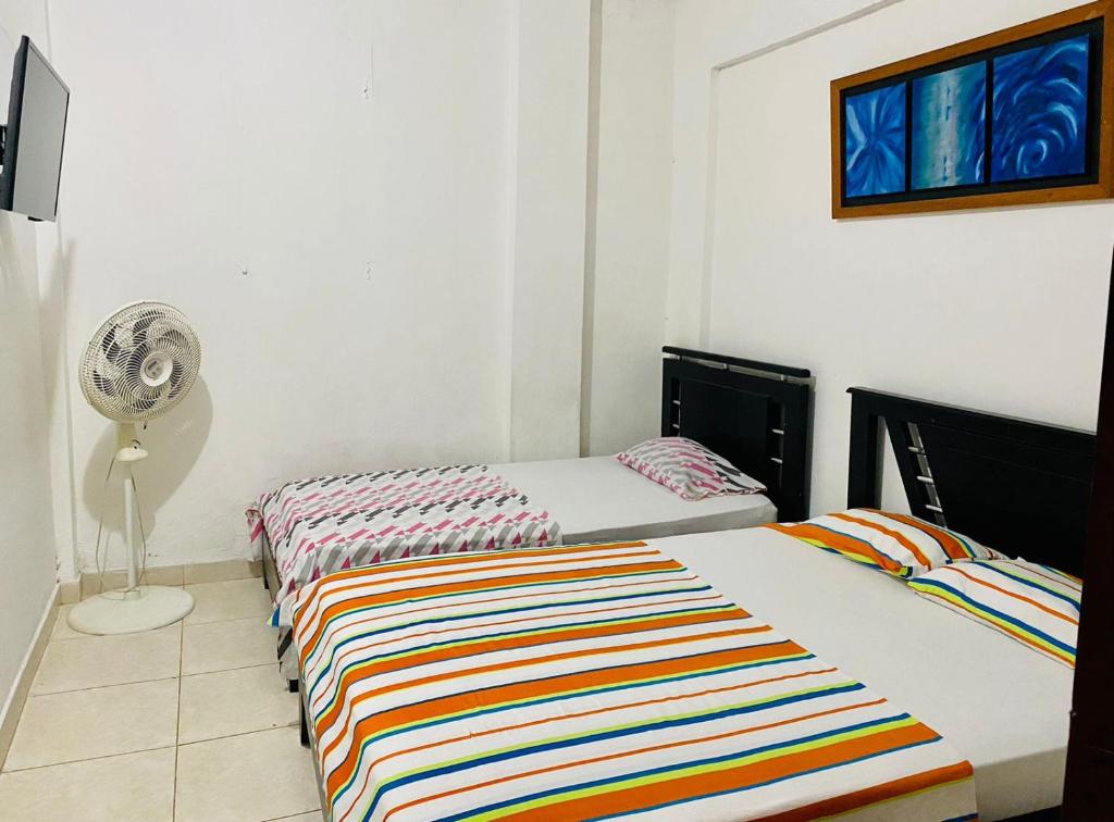 1 dormitorio con 2 camas y ventilador en Hospedaje DJ en Buga