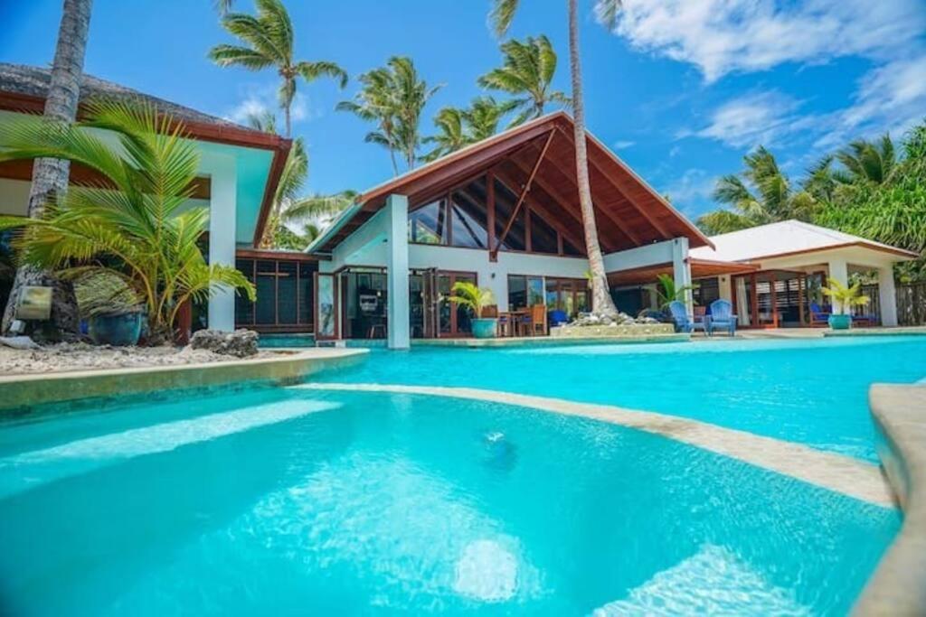 a swimming pool in front of a house at The Jewel of The Coral Coast in Tangangge