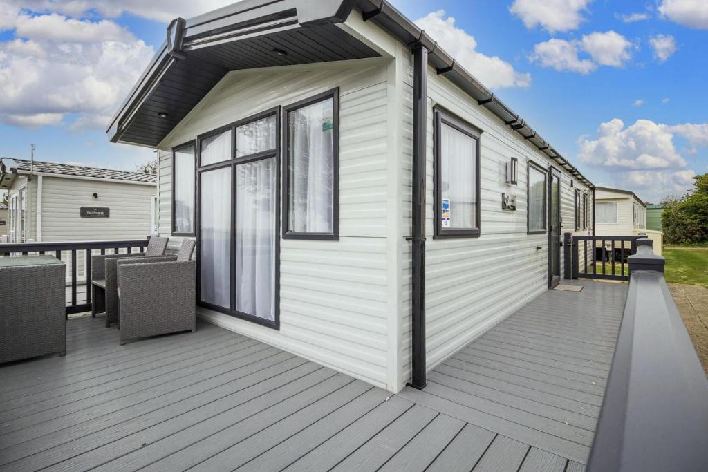 a white tiny house with a large deck at Beautiful 6 Berth Caravan, Nearby Beach In Suffolk Ref 68016bs in Lowestoft