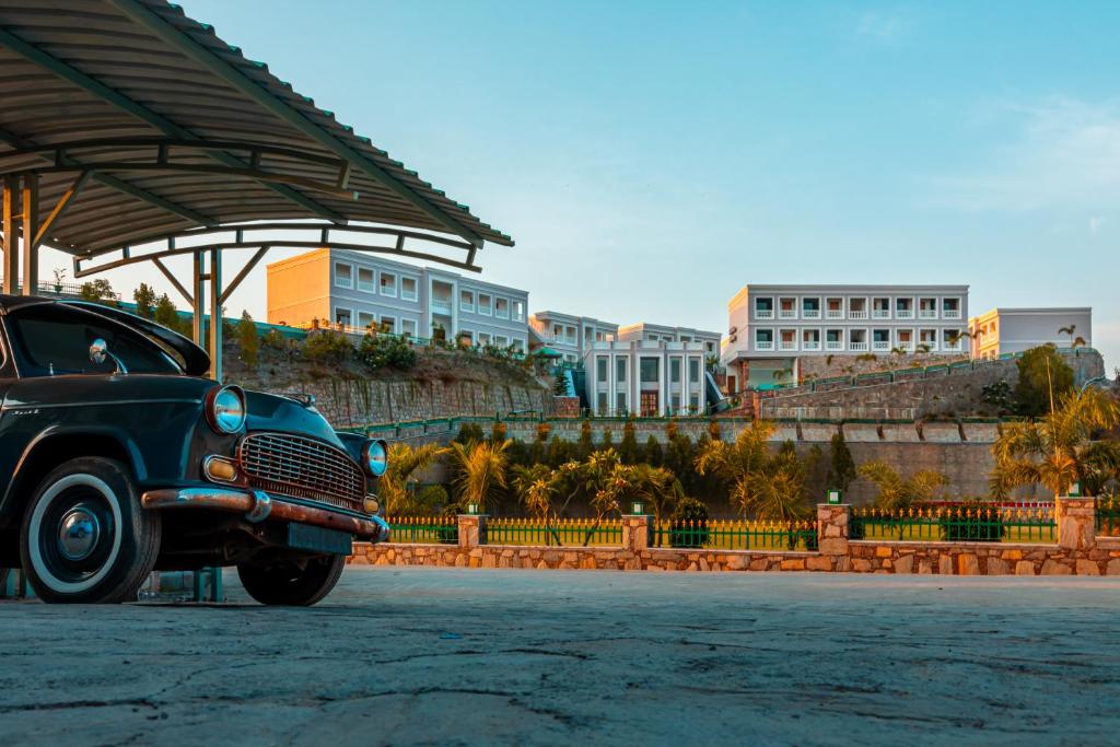 an old car parked in a parking lot with buildings in the background at Tree of Life Vantara Resort & Spa in Udaipur