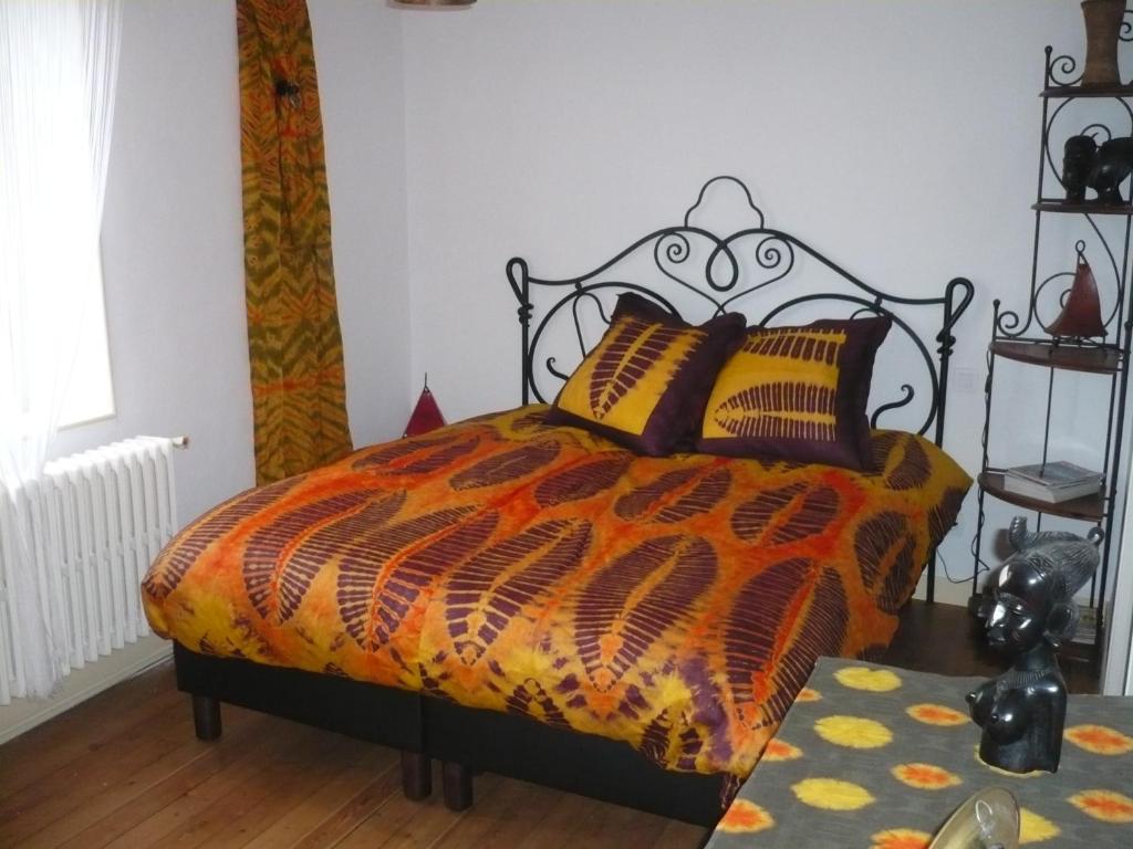 a bedroom with a bed with an orange and black comforter at Le Havre de Bennecourt in Bennecourt