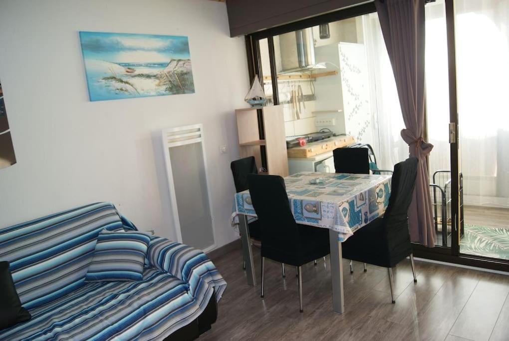 een kamer met een tafel en stoelen en een bed bij Appartement 5 Couchages tout Confort proche Mer in Le Barcarès