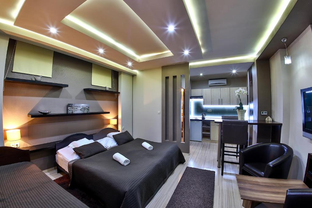 ein Schlafzimmer mit einem Bett und eine Küche in einem Zimmer in der Unterkunft Royal Apartments Hotel Kecskemét in Kecskemét