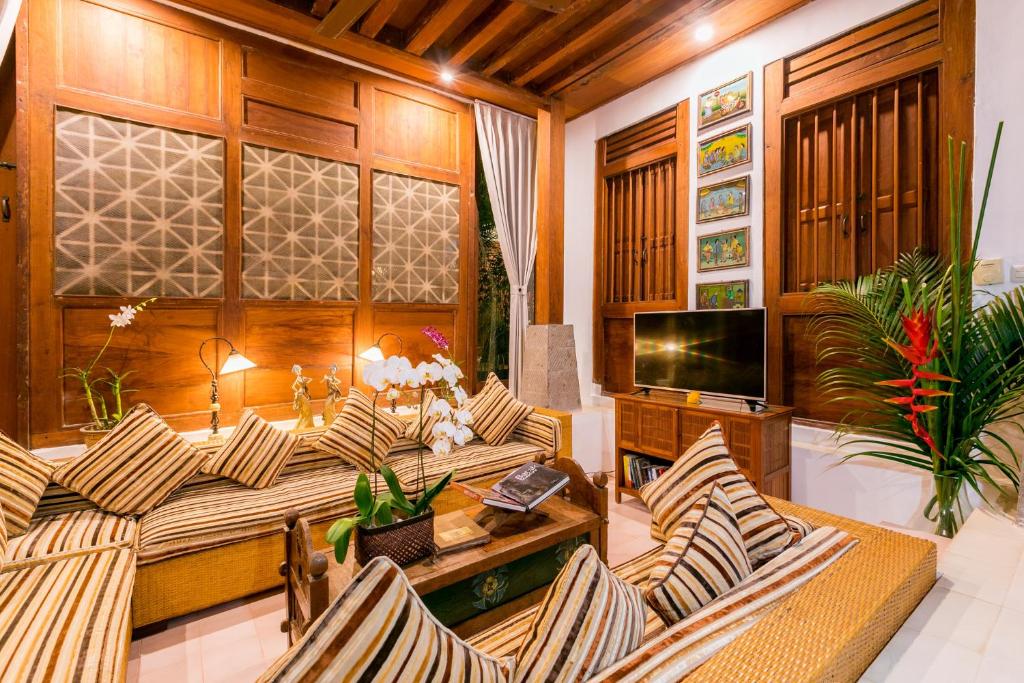 uma sala de estar com cadeiras, uma mesa e uma televisão em Villa Kampung Kecil em Sanur