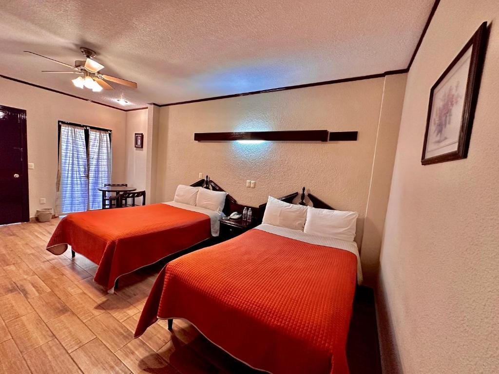 Habitación de hotel con 2 camas con sábanas rojas en Hotel Boutique Tehuacan, en Tehuacán