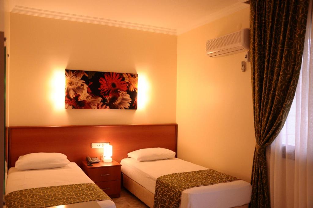 a hotel room with two beds and a painting on the wall at Lord Hotel in Çeşme