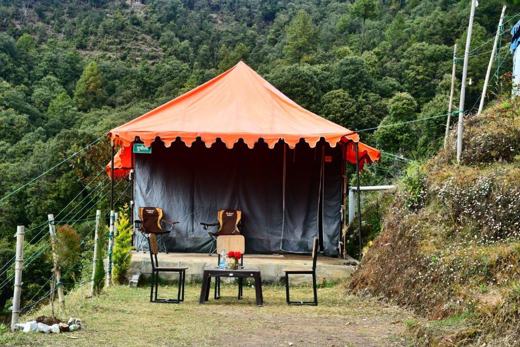 a tent with two chairs and a table in front of it at FOREST ACRES CAMPS in Mukteswar