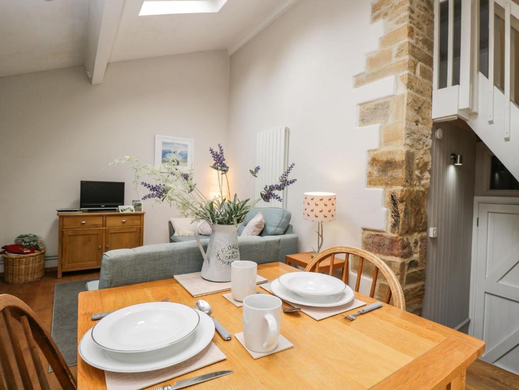 a dining room with a table and a couch at Bower Coach House in Martock