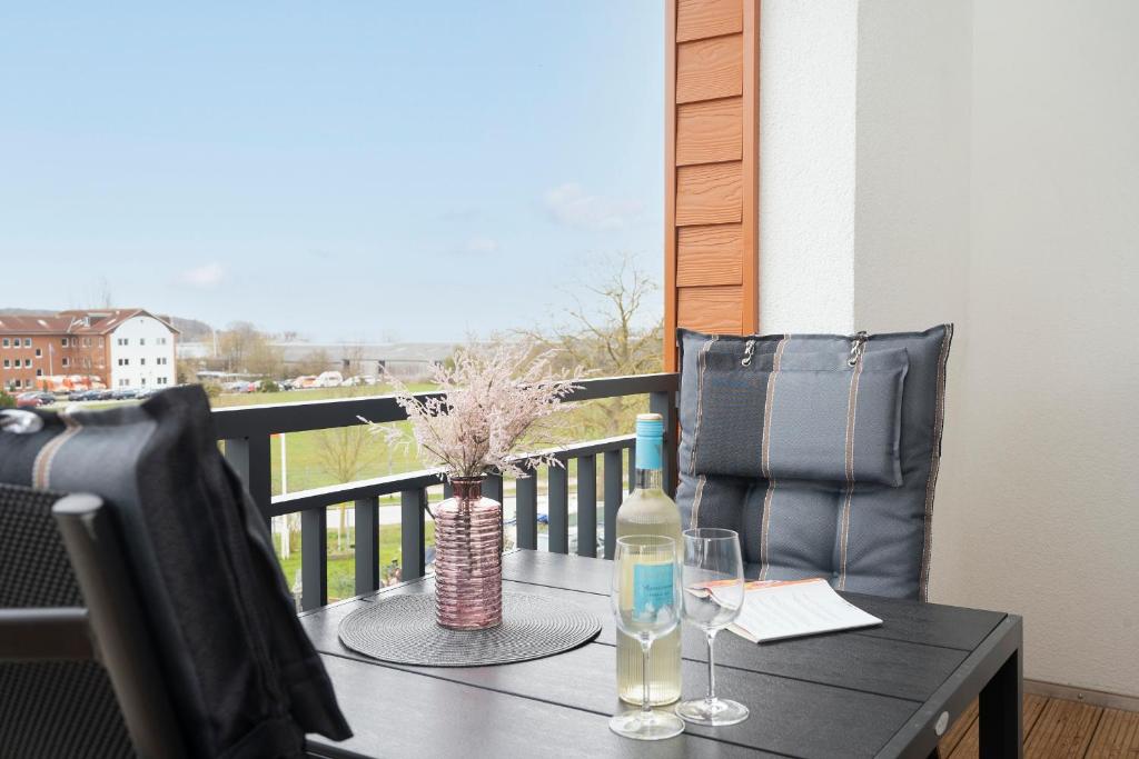 a table with a bottle and glasses on a balcony at Residenz am Yachthafen Seaside Marina in Neustadt in Holstein