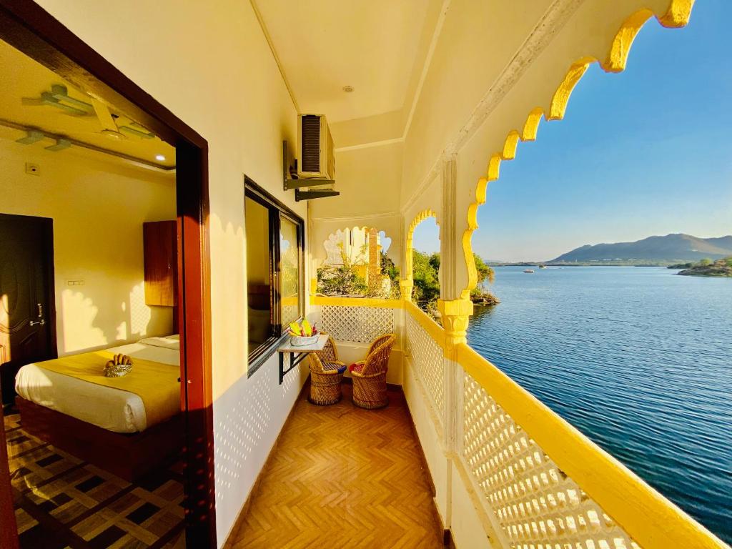 a room with a bed and a view of the water at Hotel Vallabh with lake facing balcony in Udaipur