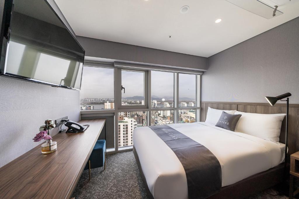 1 dormitorio con cama y escritorio con ventana en Layers Hotel Busan Hadan en Busan