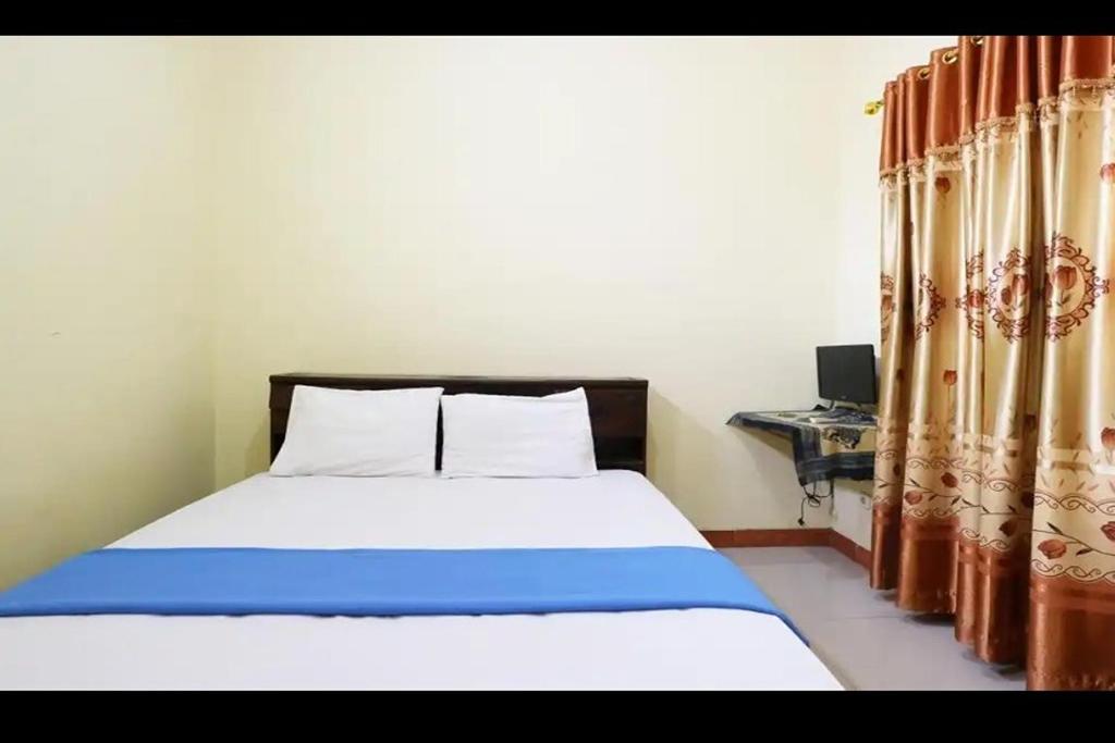 a bedroom with a bed and a desk and curtains at Hotel Serasi 2 in Tangerang