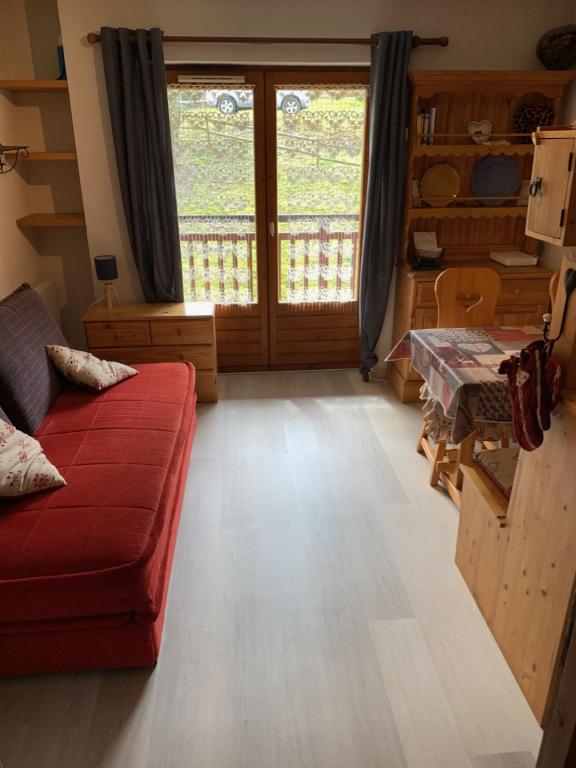 a living room with a red couch in front of a door at Studio Combloux Pied des pistes in Combloux