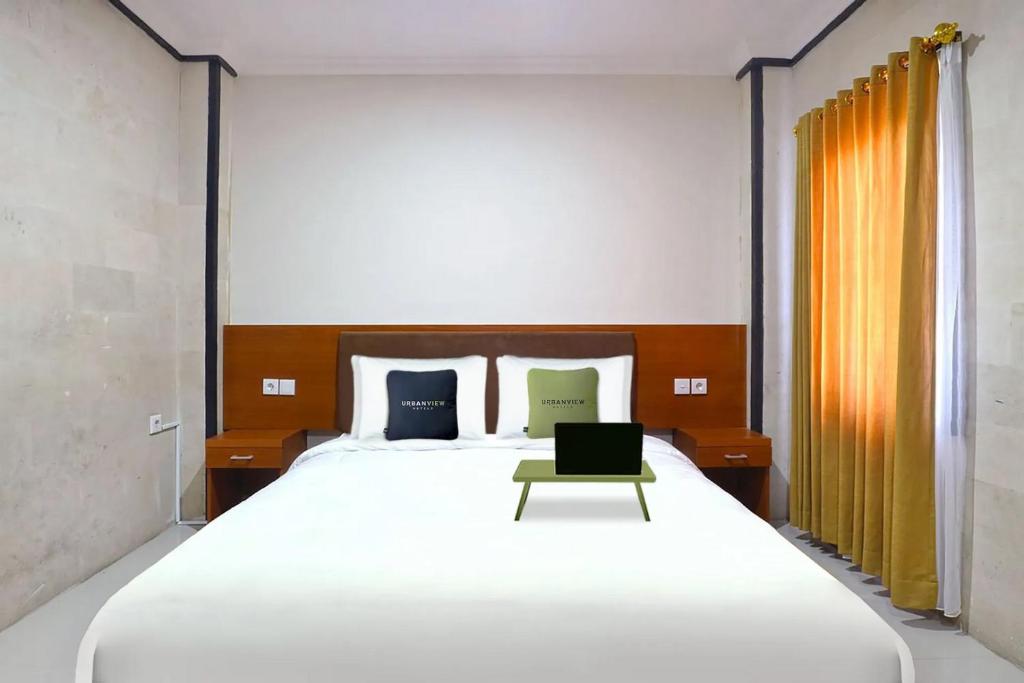 a bedroom with a large white bed and a chair at Urbanview Hotel Gita Inn Bali in Denpasar