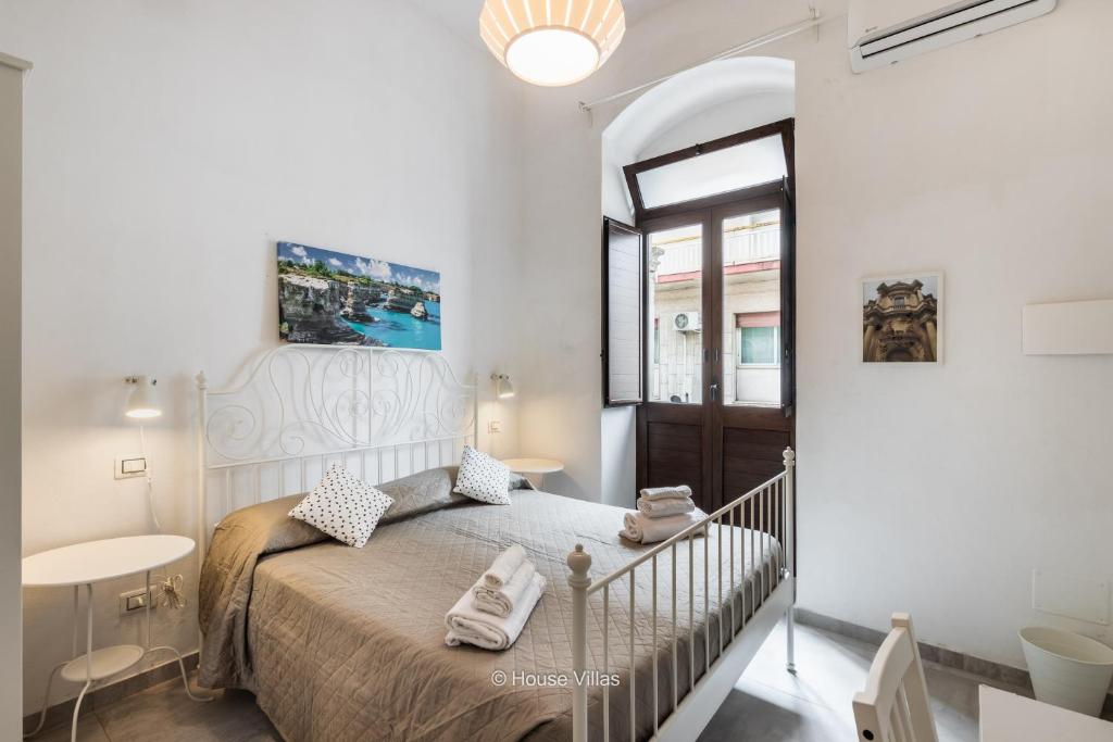 een witte slaapkamer met een bed en een raam bij Pomillo Rooms in Noto