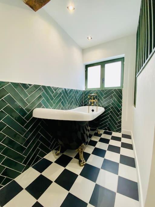 a bathroom with a tub and a checkered floor at Le Victor Hugo in Rouen