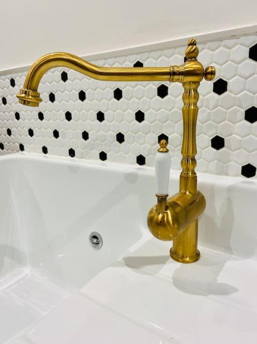 a bathroom sink with a gold faucet next to a tub at Le Victor Hugo in Rouen