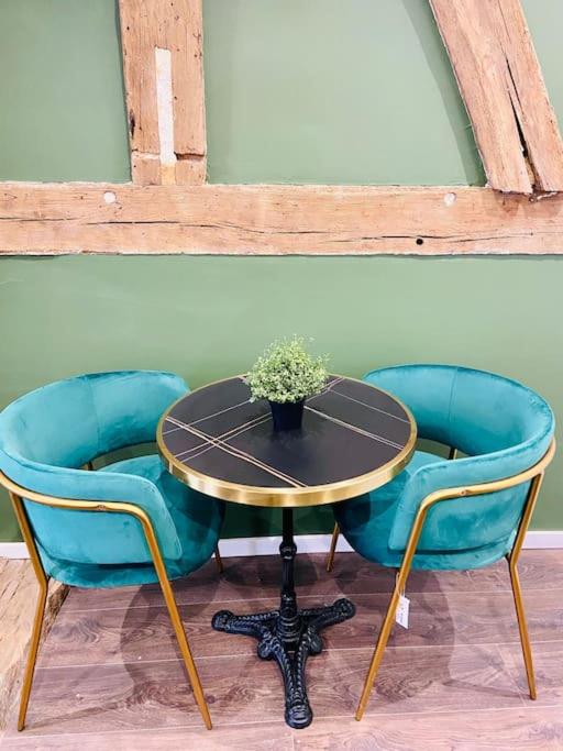 a table with two blue chairs and a table with a plant at Le Victor Hugo in Rouen