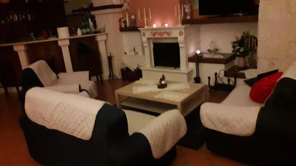 a living room with white chairs and a fireplace at Hotel Natros in Rocca Pia