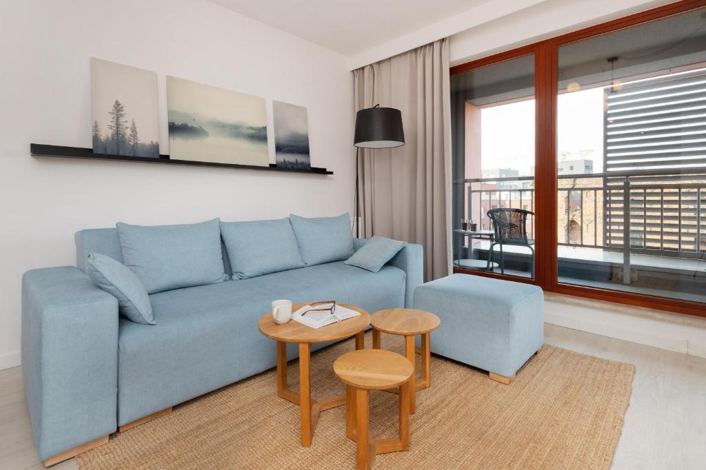 a living room with a blue couch and a table at Waterlane Apartment SPA&Wellness, Pool by Renters in Gdańsk