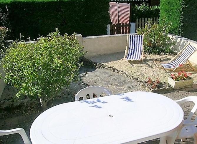 une table et des chaises blanches dans une cour avec un arbre dans l'établissement La Palmyre - VILLA MITOYENNE dans Les Maisons du Lac - TERRASSE PRIVATIVE, aux Mathes