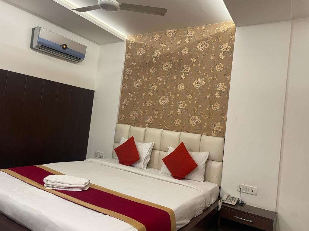 Hotel Areeba by The Golden Taj Group & Hotels في آغْرا: غرفة نوم بسرير ومخدات حمراء