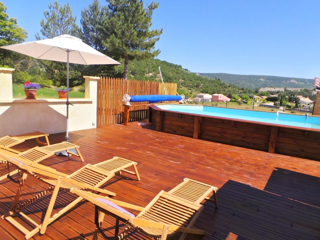 a deck with chairs and an umbrella and a pool at Le Mas Des Ferrayes in Ongles