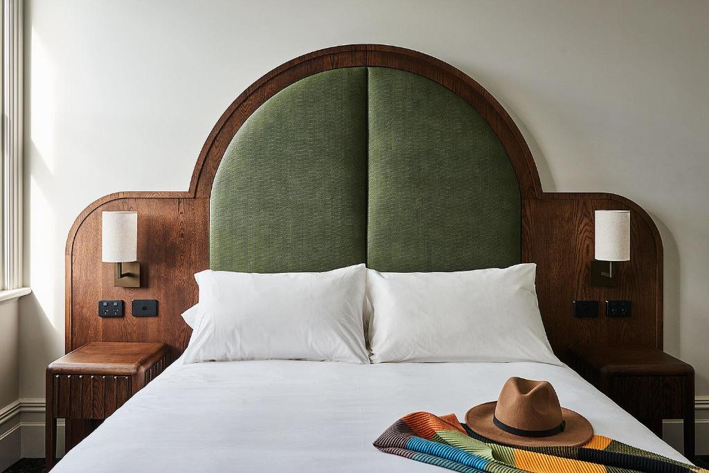a bed with a green headboard with a hat on it at Portarlington Grand Hotel in Portarlington