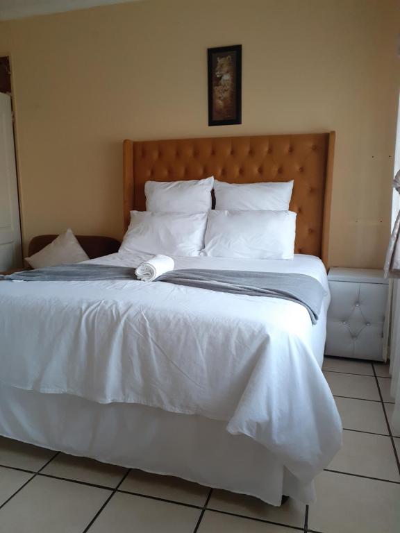 1 cama blanca grande con sábanas y almohadas blancas en Kwesethu Guesthouse, en Empangeni