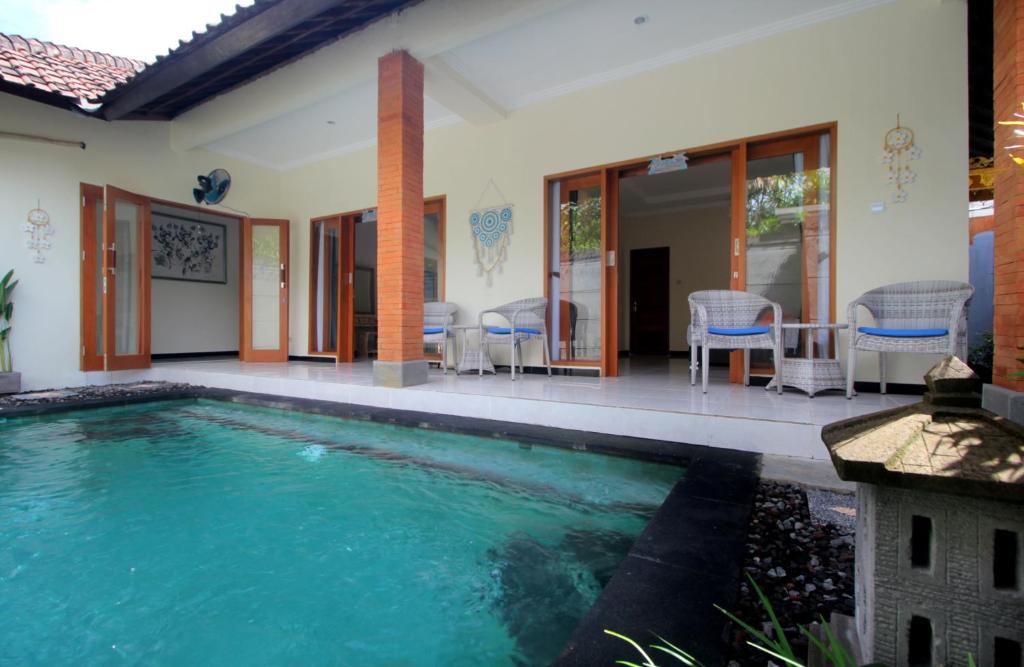 a swimming pool in front of a house at Shine Villa Sanur in Sanur