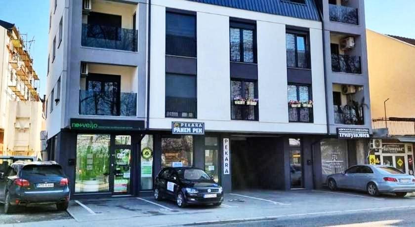 dos autos estacionados en un estacionamiento frente a un edificio en Apartman 222 en Brčko