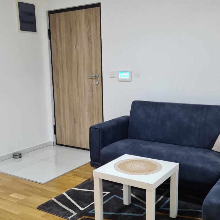 a living room with a blue couch and a table at Apartman 222 in Brčko