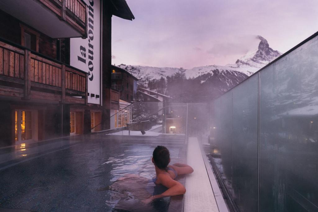 una donna seduta in una piscina con una montagna di la couronne Hotel & Spa a Zermatt
