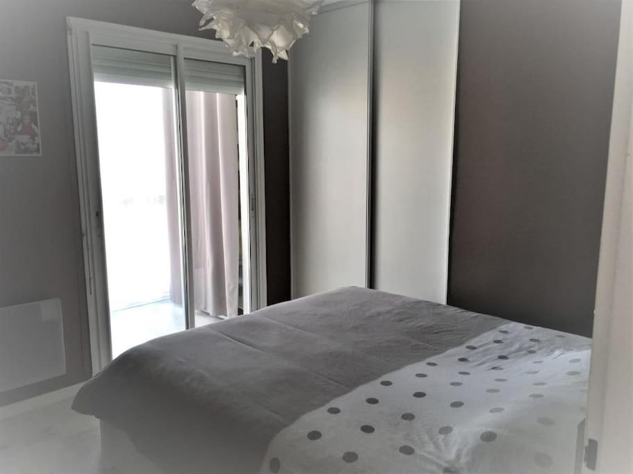 sypialnia z łóżkiem i dużym oknem w obiekcie Appartement T3 proche de la mer w mieście Narbona