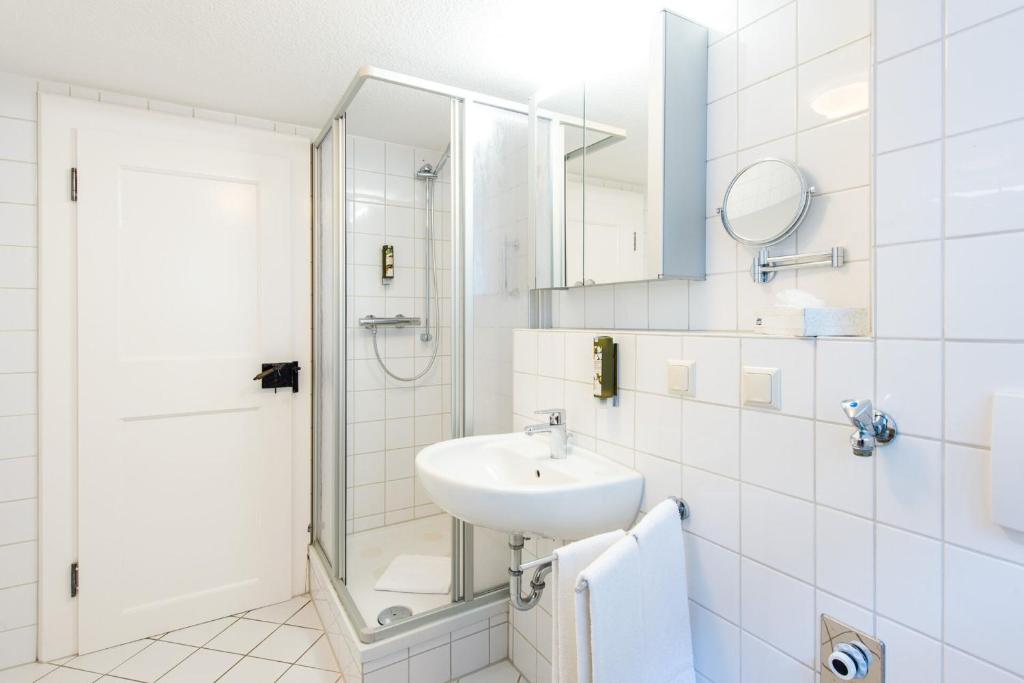 ein weißes Bad mit einem Waschbecken und einer Dusche in der Unterkunft Ferienwohnung 2 - Marktkirchhof in Quedlinburg