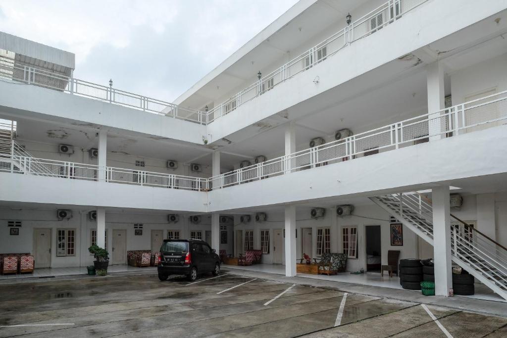 a large white building with a car parked in a parking lot at RedDoorz Plus near UMS Solo in Solo