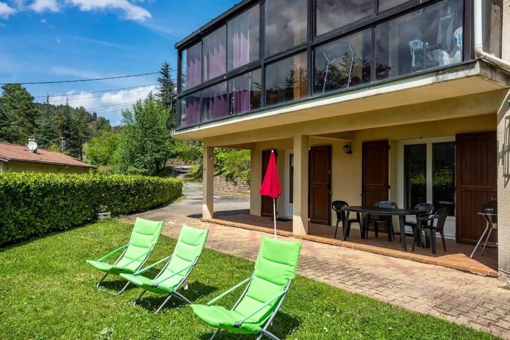 een patio met groene stoelen en een tafel voor een huis bij Gites en Cevennes "Chez Steloune" in Génolhac
