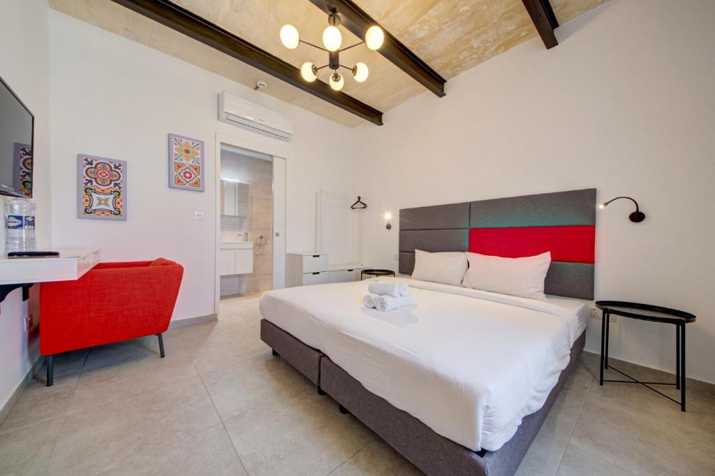 um quarto com uma cama grande e uma cadeira vermelha em Casa Domenico 3 em Valletta