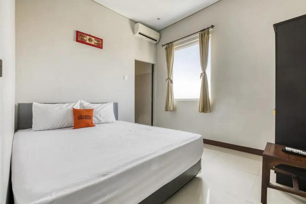 a bedroom with a large white bed and a window at KoolKost at Bypass Nusa Dua in Nusa Dua